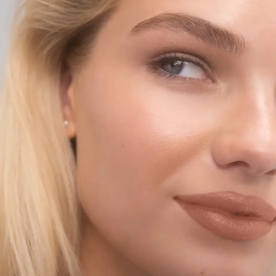 Close-up of a woman's face with smooth skin and nude lipstick. Text: "JAYNE".