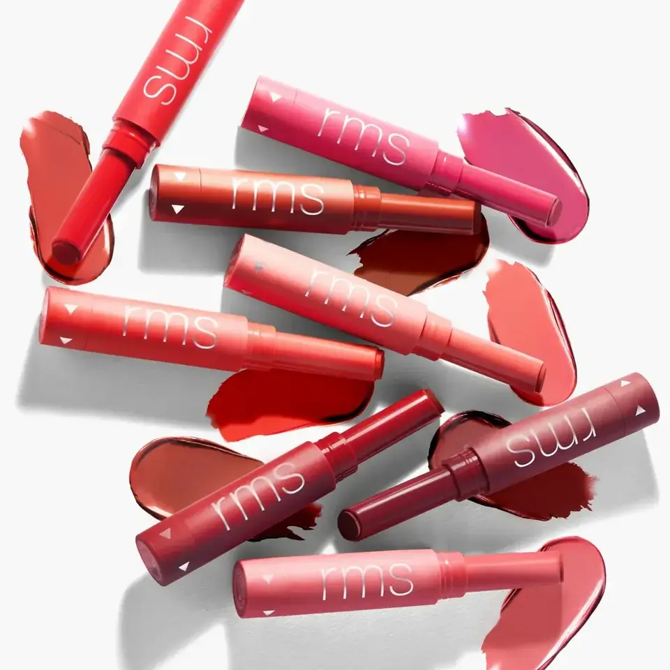 Assorted RMS lipsticks with swatches in various red and pink shades on a white background.