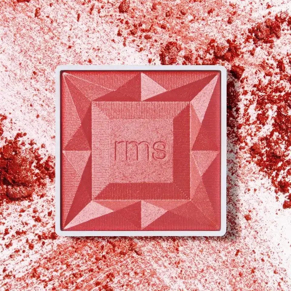 Red blush compact with "rms" logo, surrounded by scattered blush powder.