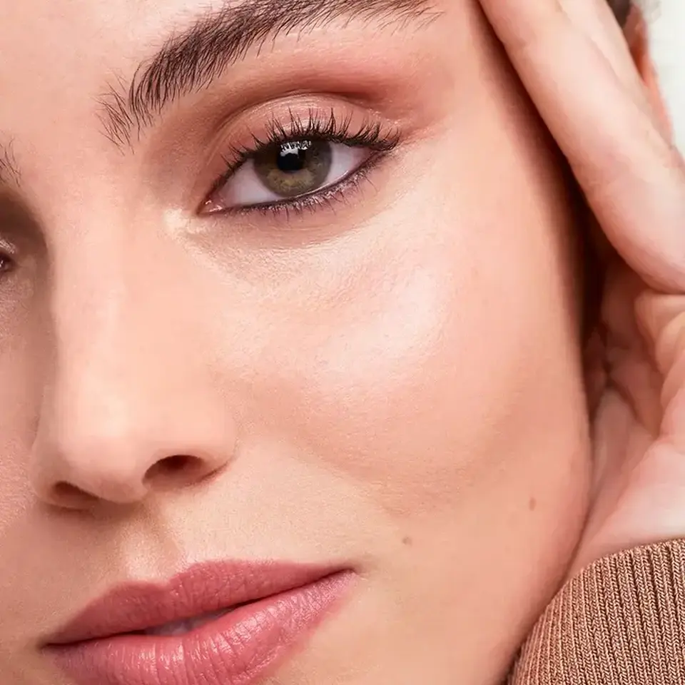 Close-up of a person's face with smooth skin, pink lips, and defined eyebrows.