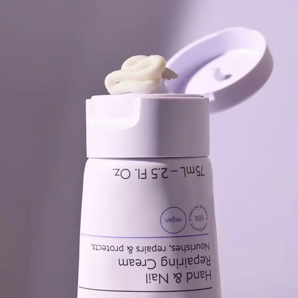 Open tube of hand and nail cream with cream on the lid.
