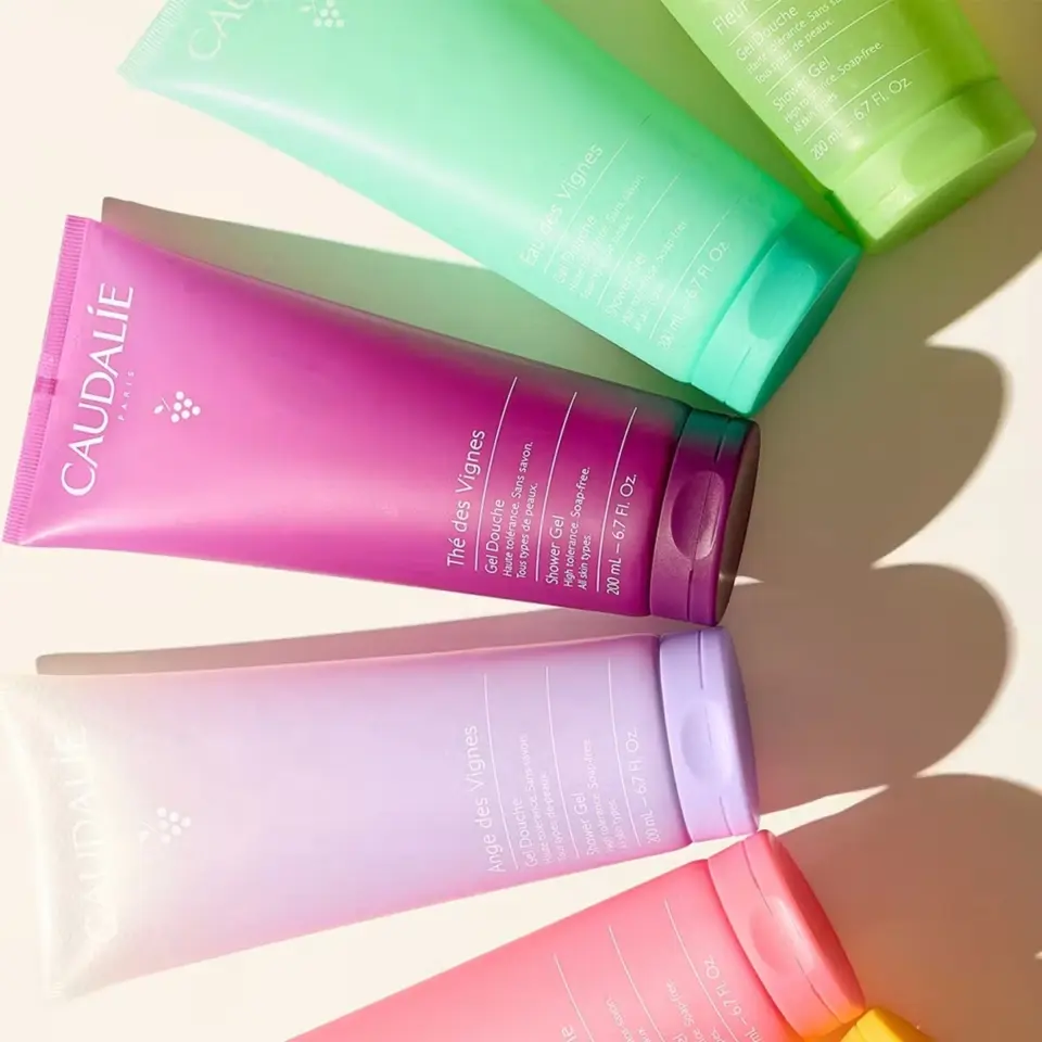 Colourful Caudalie shower gel tubes arranged on a light surface.