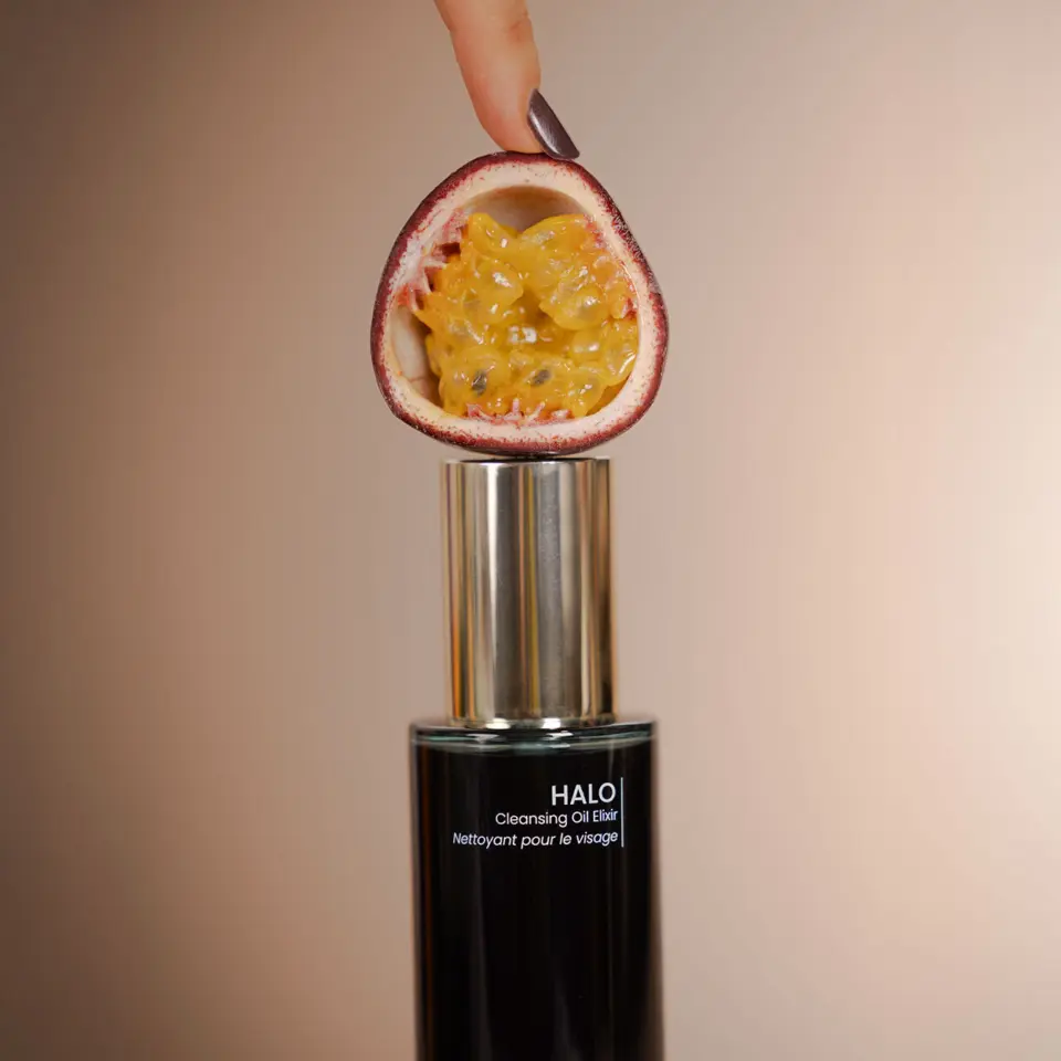 Passion fruit half above Halo Cleansing Oil Elixir bottle.