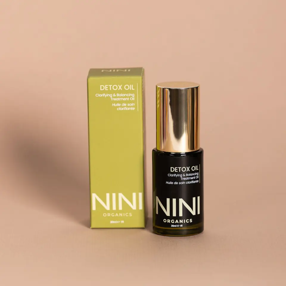 NINI Organics Detox Oil bottle and box on a beige background.
