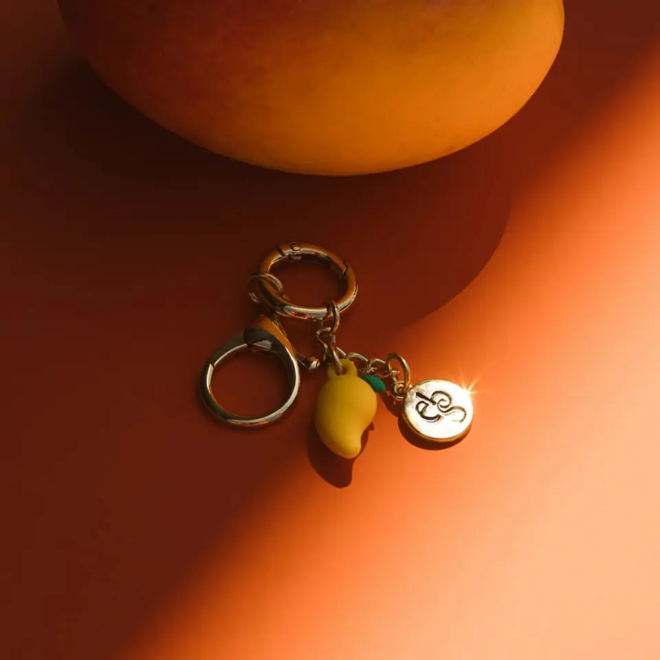Keyring with mango charm and engraved disc on orange surface.