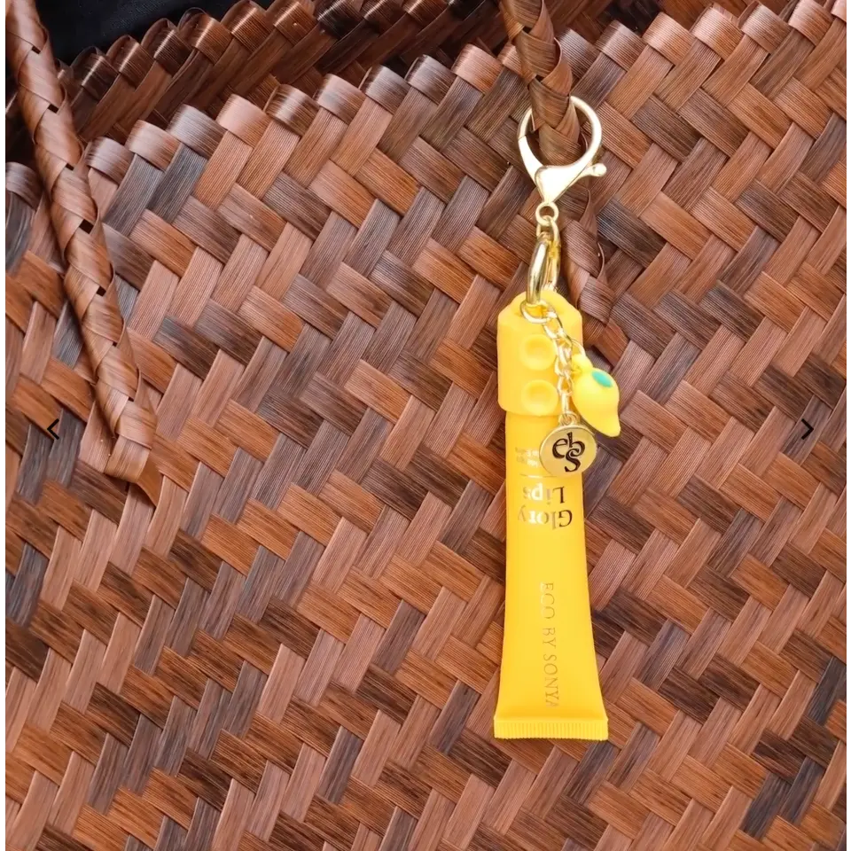 Yellow lip balm tube with keychain on woven brown bag.