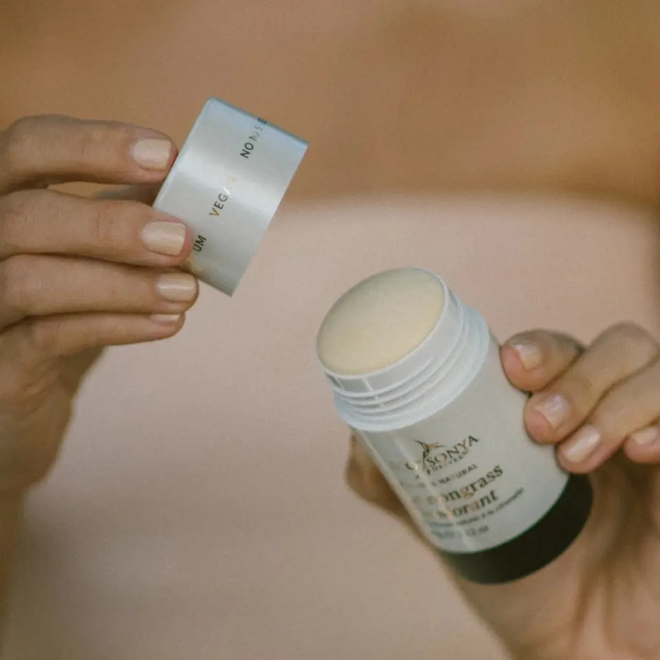 Person holding a lemongrass deodorant stick with the lid removed.