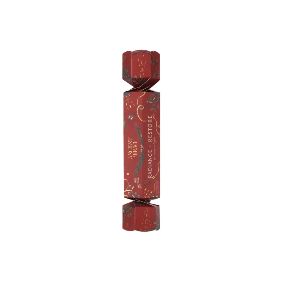 Red cracker with "Radiance + Restore" text and festive design.