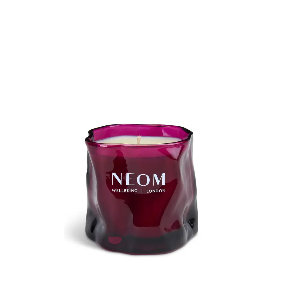 Purple glass candle with "NEOM Wellbeing London" text.