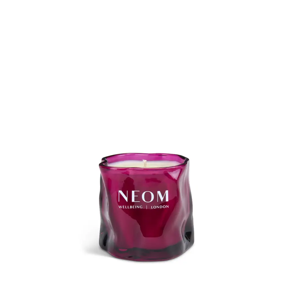 Purple glass candle with "NEOM Wellbeing London" text.