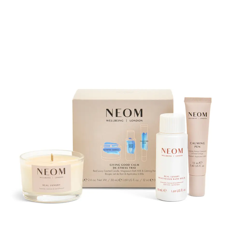 NEOM de-stress trio with candle, bath milk, and calming pen in front of branded box.