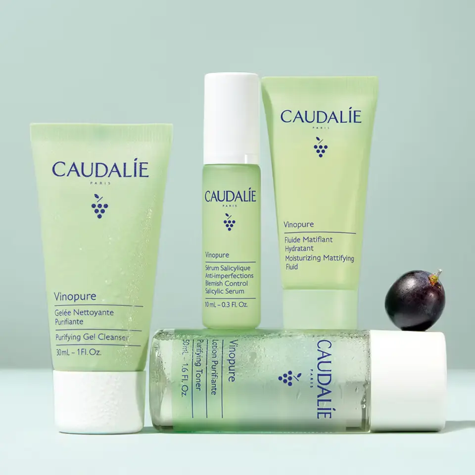 Caudalie Vinopure skincare products with grape on light green background.