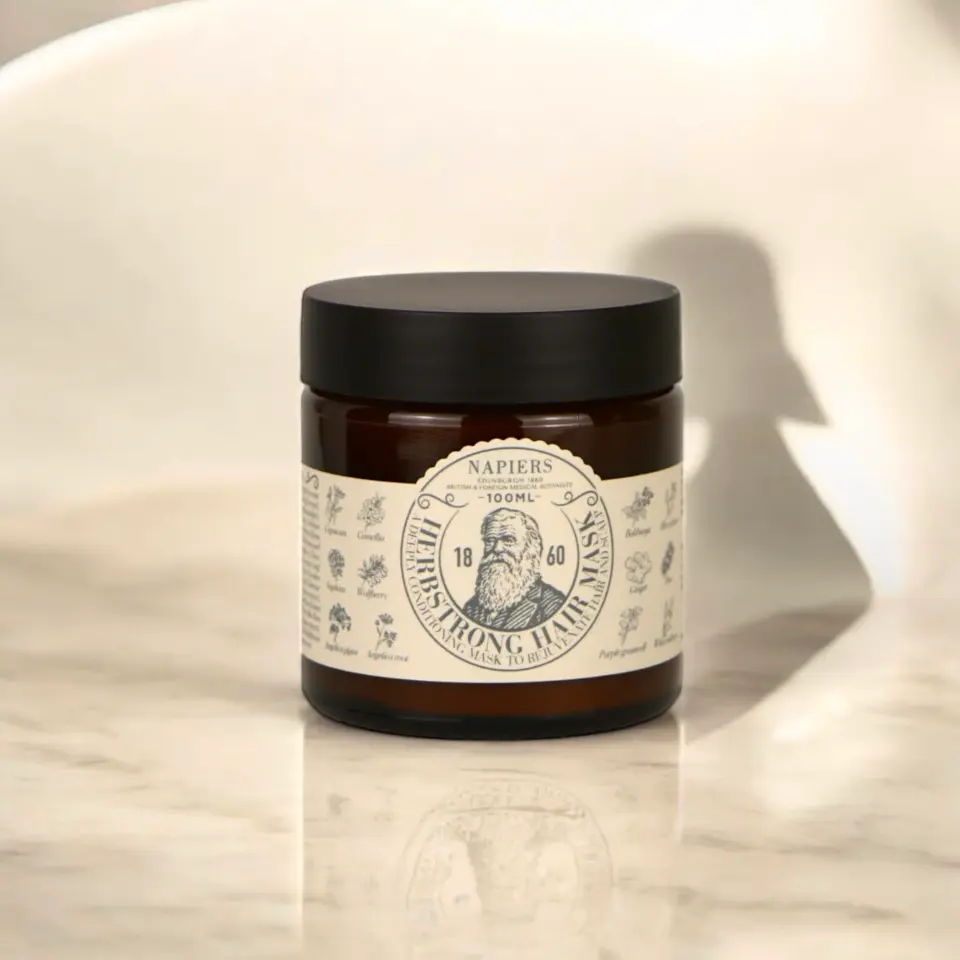 Brown jar of Napiers Herbfstrong Hair Mask on a marble surface.