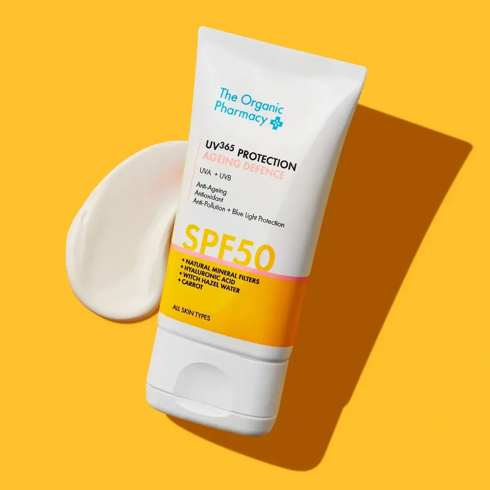 The Organic Pharmacy SPF 50 sunscreen tube on yellow background.