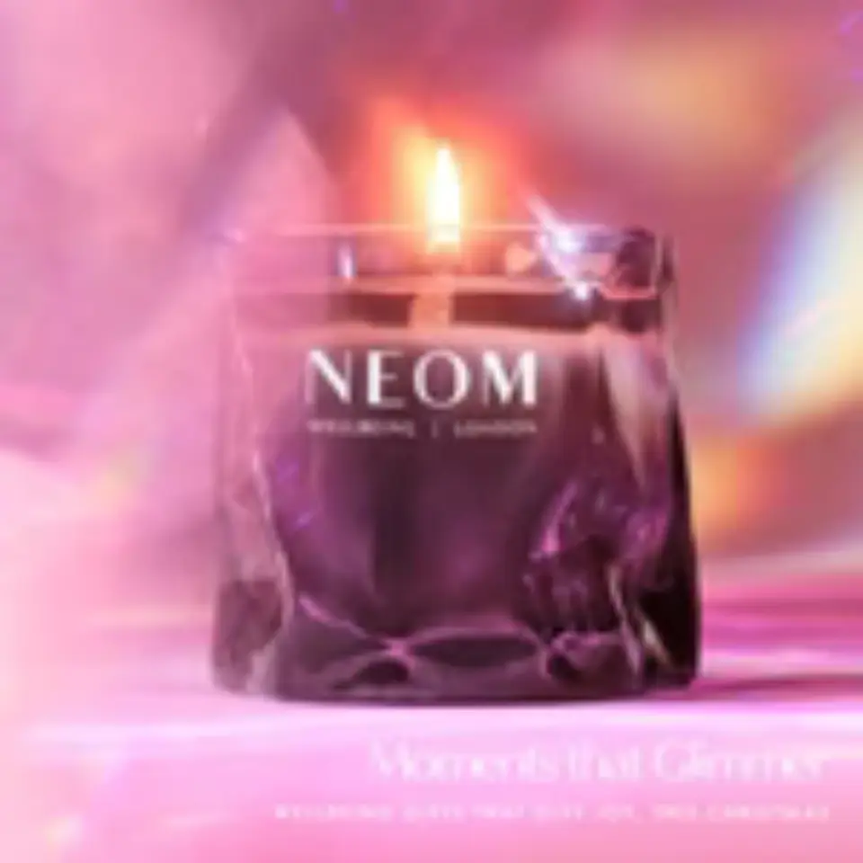 Purple NEOM candle with flame, text: "Moments that Glimmer".