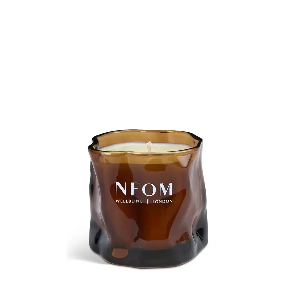 Brown glass candle with "NEOM Wellbeing London" text.
