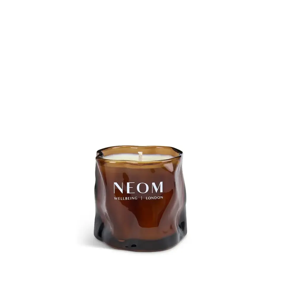 Brown glass candle with "NEOM Wellbeing London" text.