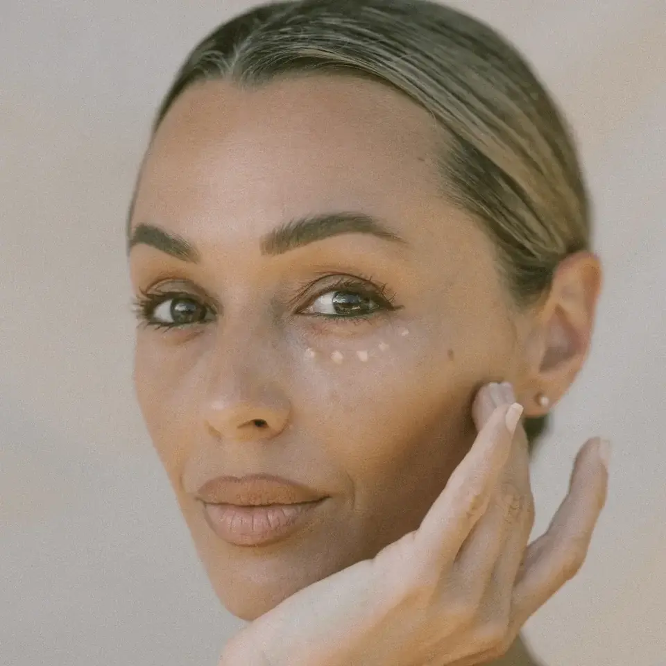 Woman applying cream under her eyes with fingers.