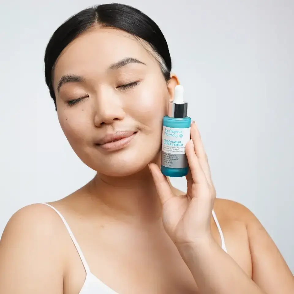 Person holding The Organic Pharmacy Niacinamide Ultra 5 Serum bottle.