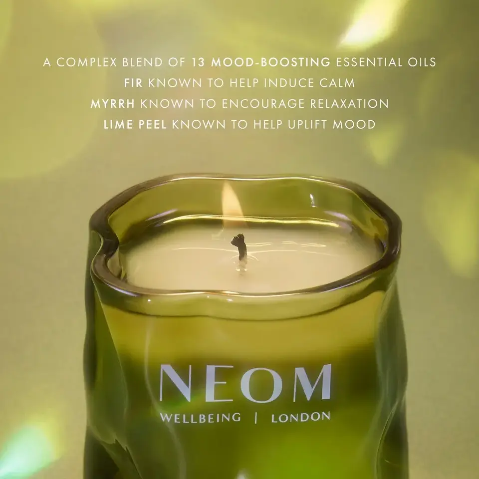 Green NEOM candle with text about mood-boosting essential oils.