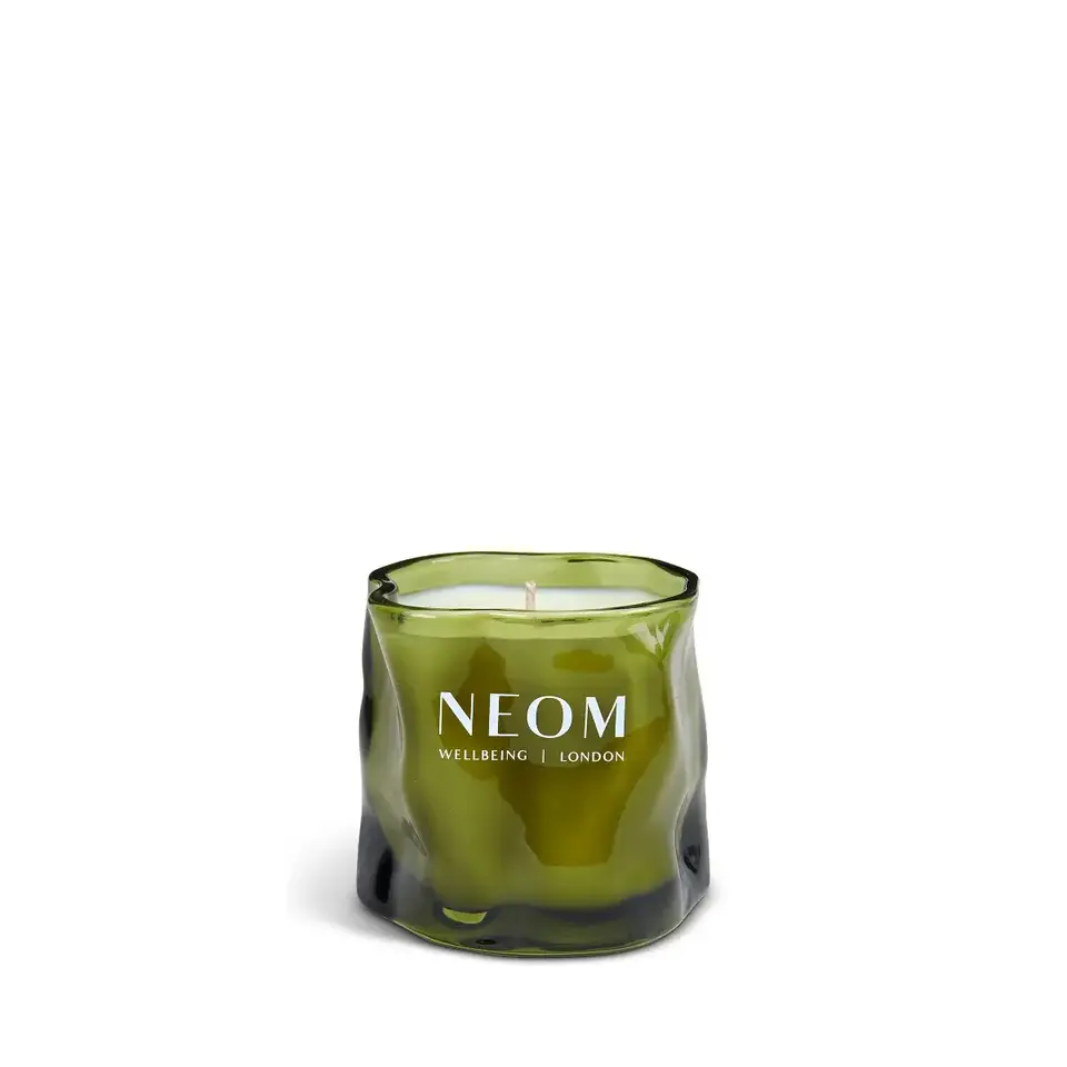 Green glass candle with "NEOM Wellbeing London" text.