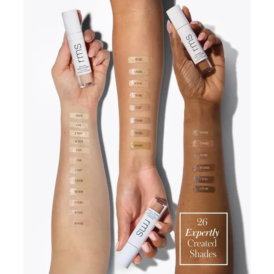 Three arms with 26 foundation shades swatched. Each holds an RMS bottle.