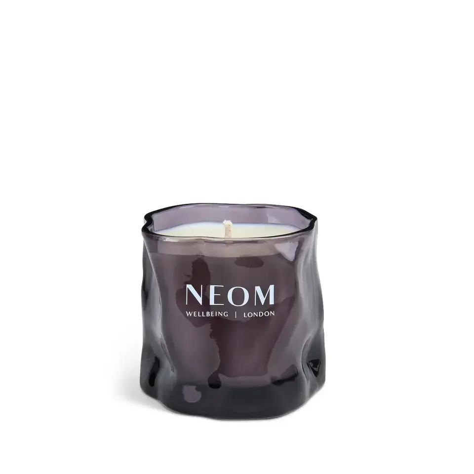 Purple glass candle with "NEOM Wellbeing London" text.