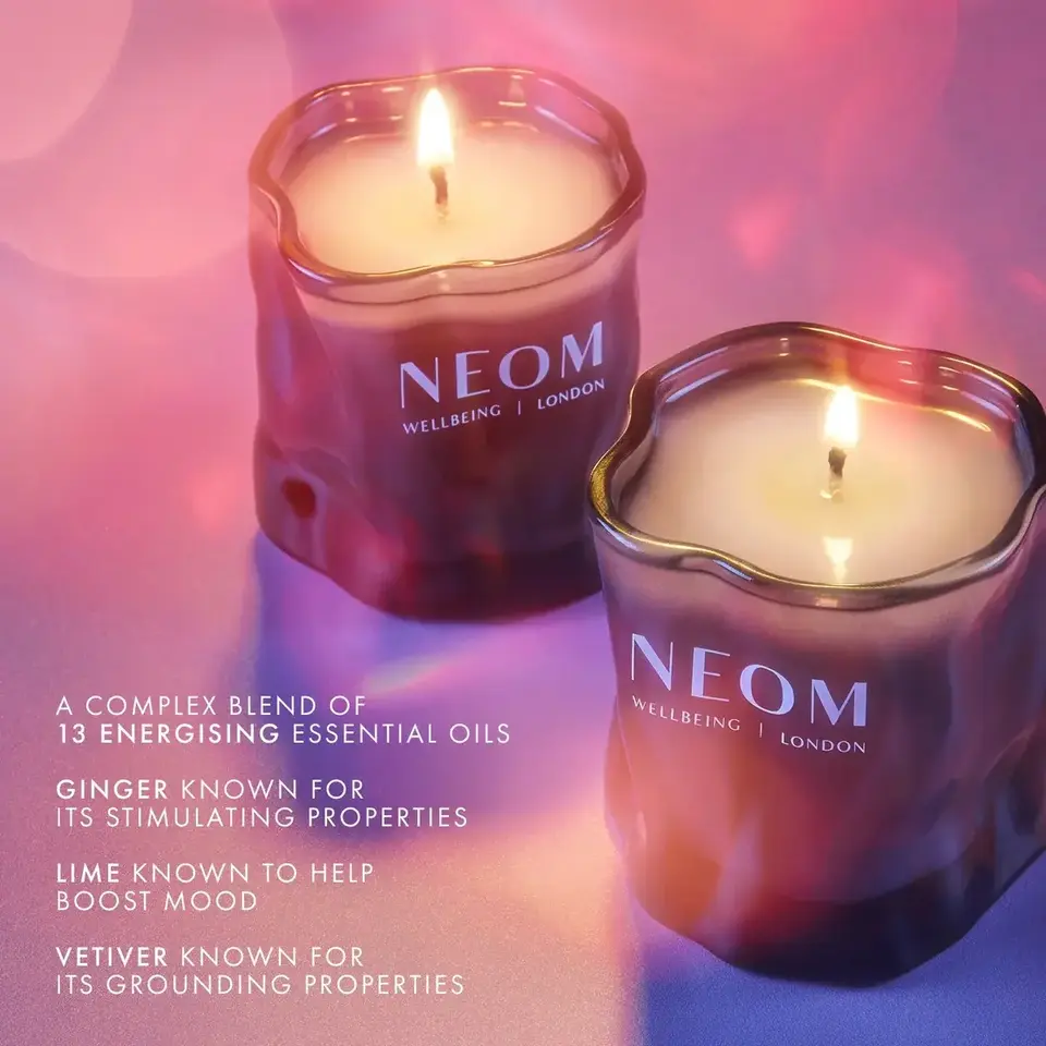 Two lit NEOM candles with text about essential oils: ginger, lime, and vetiver properties.