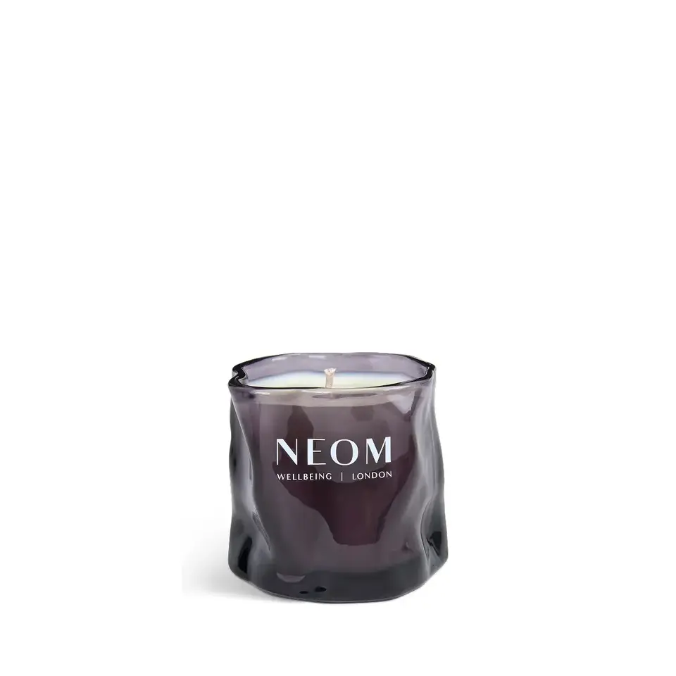 Purple glass candle with "NEOM Wellbeing London" text.