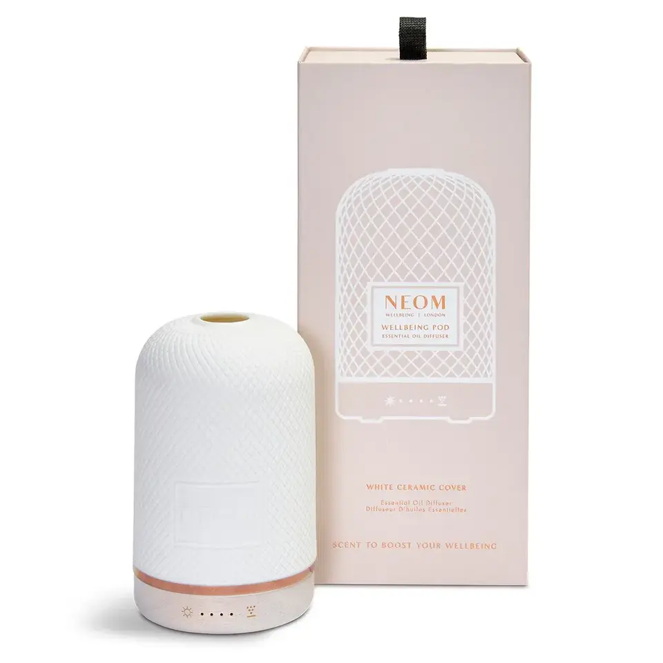 White ceramic essential oil diffuser with packaging. Text: "NEOM Wellbeing Pod".