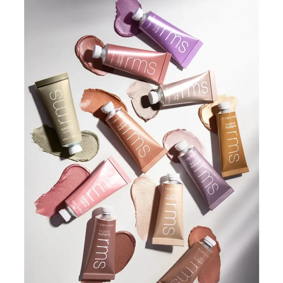 Assorted rms beauty cream tubes with swatches on a white background.