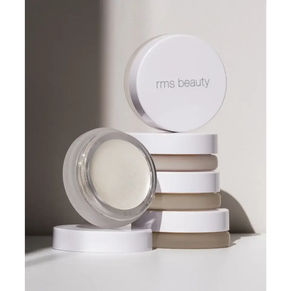 Stack of rms beauty containers with one open, revealing a cream product inside.