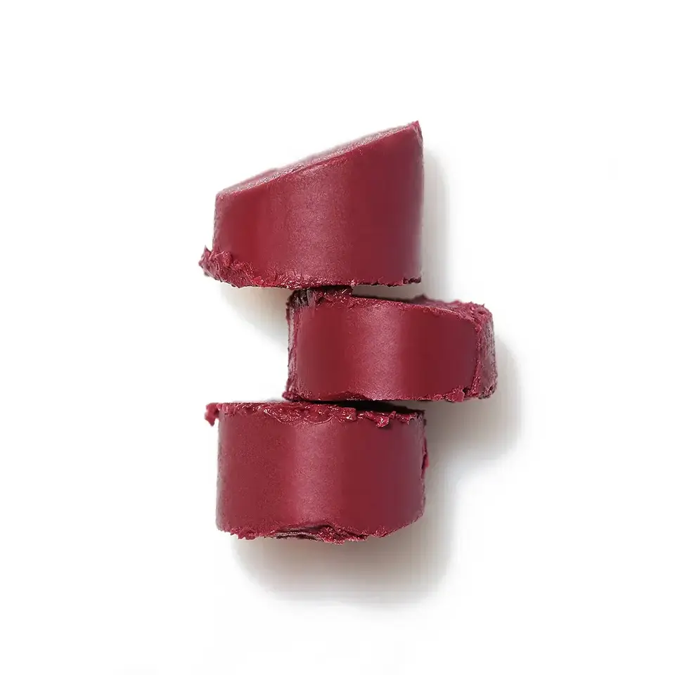 Three stacked slices of deep red lipstick on a white background.