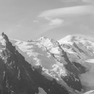 Snow-covered mountain peaks under a cloudy sky.