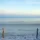 Sandy beach with calm sea and clear sky, two wooden posts in foreground.