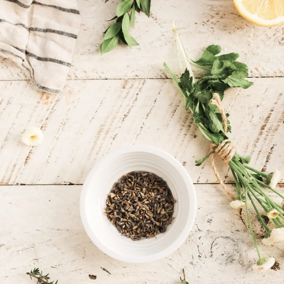Herbs, lemon halves, and salt on a wooden table with a striped cloth.