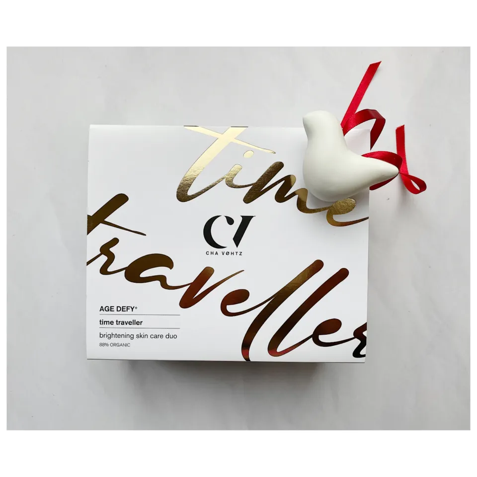 White box with gold text "time traveller", red ribbon, and white bird ornament.