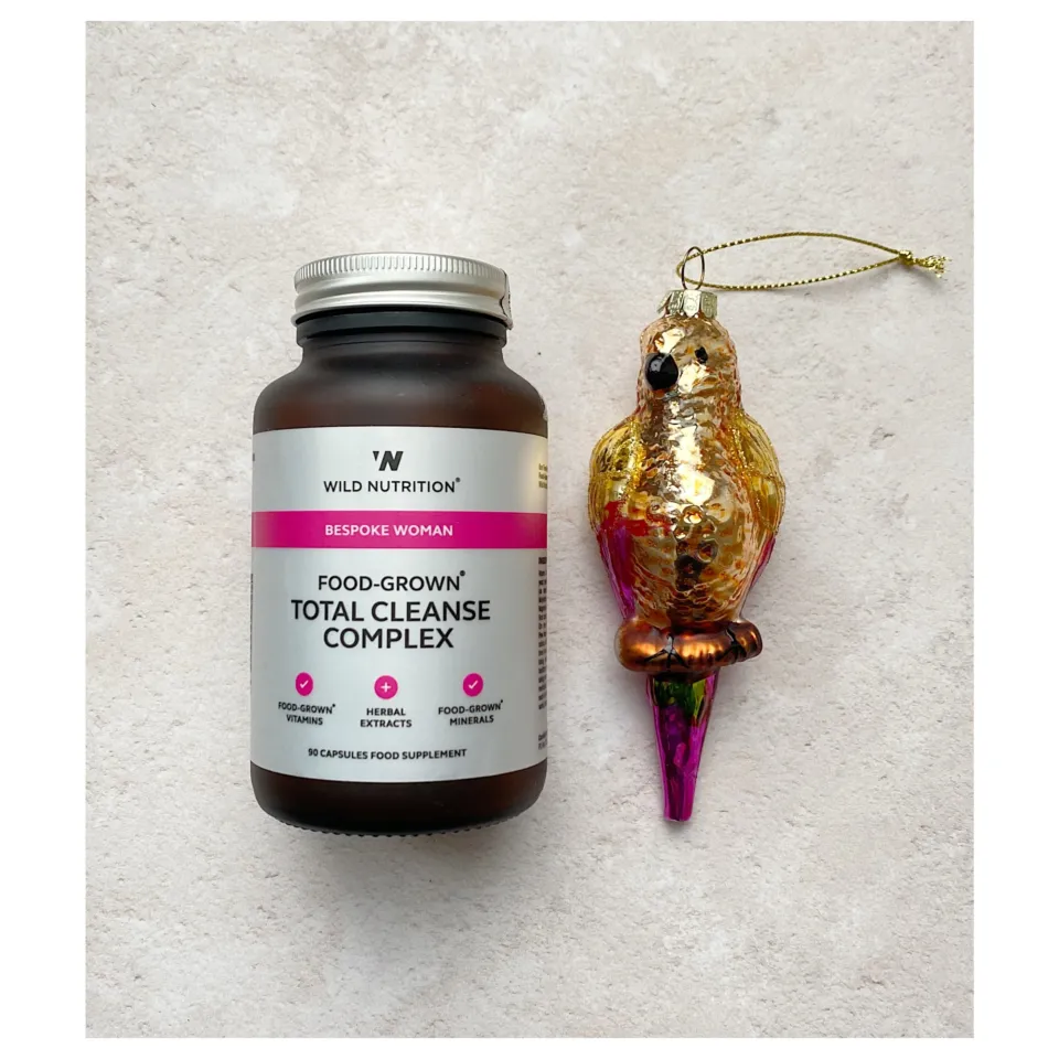 Supplement bottle labelled "Total Cleanse Complex" beside a decorative bird ornament.