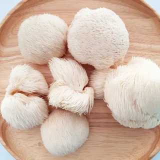 Lion's mane mushrooms on a round wooden plate.