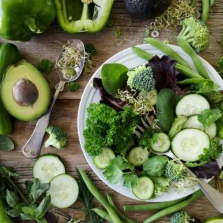 Salad with cucumber, avocado, broccoli, and greens on a wooden table.