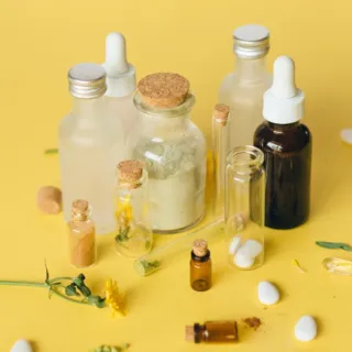 Assorted skincare bottles and capsules on a yellow background.