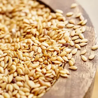 Sesame seeds spilling from a wooden bowl.