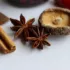 Cinnamon sticks, star anise, and a dried mushroom on a white surface.