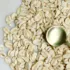 Rolled oats scattered on a surface with a gold spoon on top.