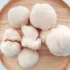 Lion's mane mushrooms on a round wooden plate.