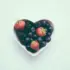 Heart-shaped bowl with strawberries, blackberries, and blueberries on a light background.