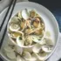 Clams in a white bowl on a plate with chopsticks and a napkin.