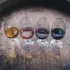Four wine glasses with different coloured wines on a wooden barrel.