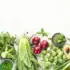 Assorted green vegetables and fruits on a white background.