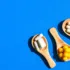 Wooden spoons with white capsules and yellow tablets on a blue background.
